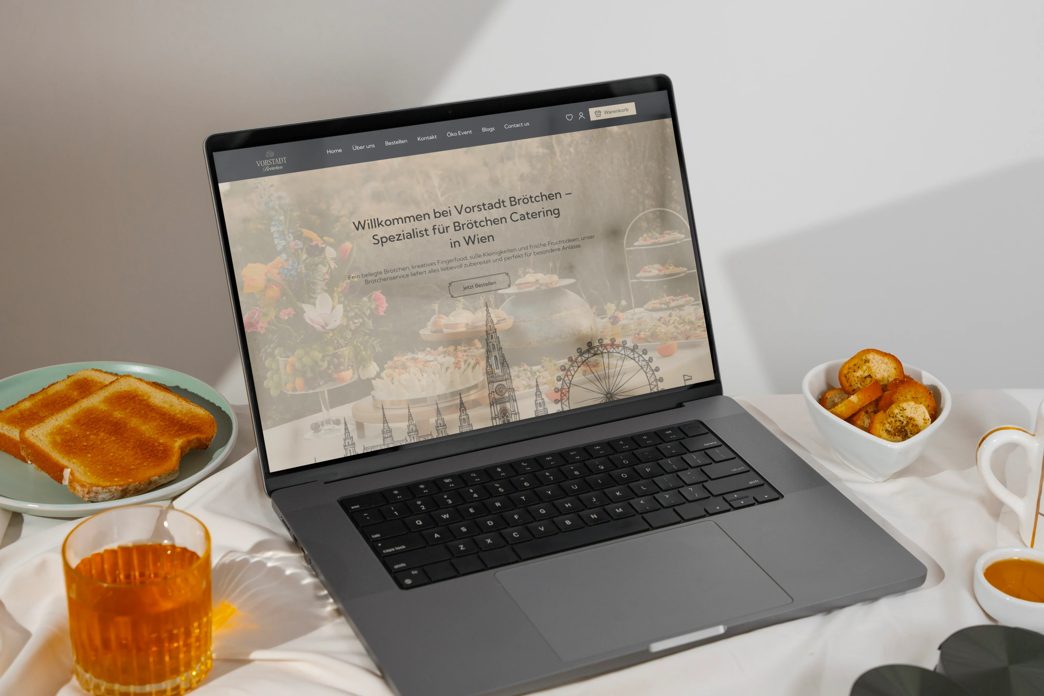 Vorstadt Brötchen home page on a laptop, on a breakfast table with toast and tea